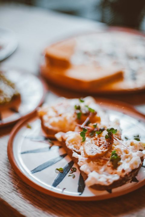 Delicious gourmet toast topped with cheese and microgreens on a stylish plate.